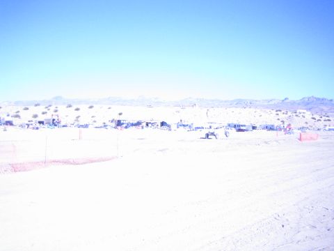 1990 Ford Bronco - overexposed desert race course shows faint pit camps and orange fencing strung along a wide sandy expanse.