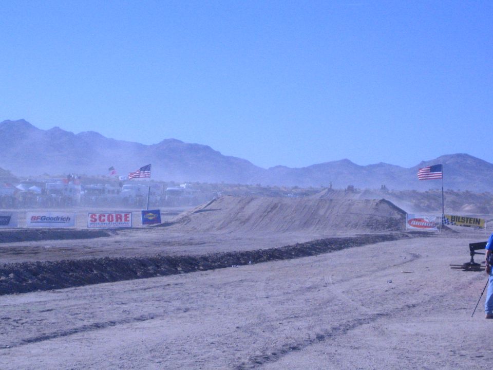 Desert race course with dirt berm, American flags and sponsor banners