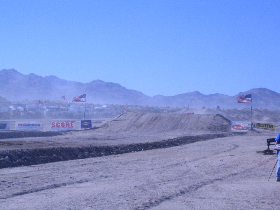 Desert race course with dirt berm, American flags and sponsor banners