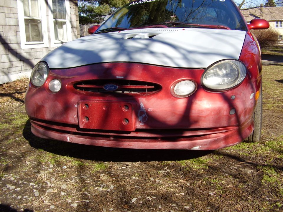 Red 1996 Ford Taurus front end with a white hood and visible damage on the bumper