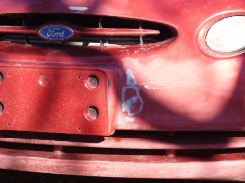 1997 Ford Taurus - Front view of a red 1997 Ford Taurus showing the grille, bumper, and headlight, with visible repair work on the bumper.