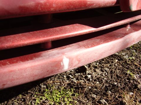 1997 Ford Taurus - Close-up view of a red car grille, showing horizontal bars and a scuff mark on the lower section.