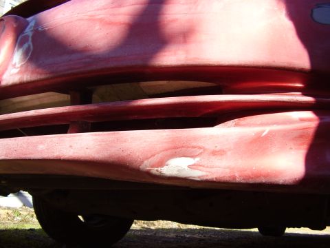 1997 Ford Taurus - The front bumper and grille area of a red vehicle shows signs of repair and wear.