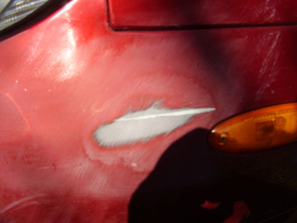 Red car fender with primer patch and orange turn signal light