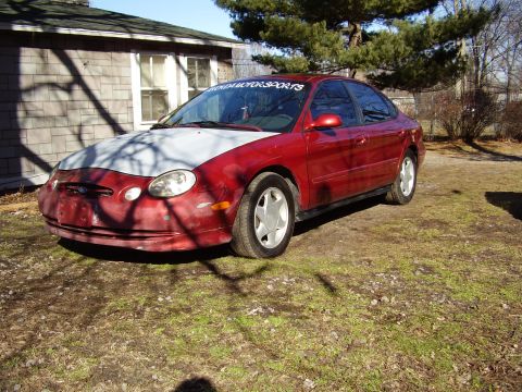 1997 Ford Taurus - This red sedan, likely a 1998 model, has a hood that has been primed and is awaiting paint.