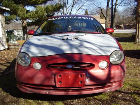 1997 Ford Taurus - This red car, identified as a 1997 Ford Taurus, is parked outdoors with a white hood.