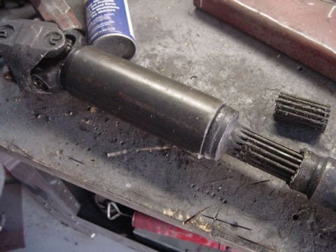 1971 Ford Bronco - A close-up view of a driveshaft component, showing its splined end and a can of lubricant on the workbench.