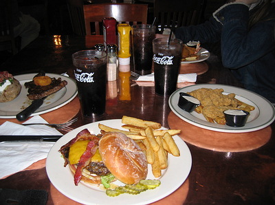 1999 Ford Crown Victoria - A table is set with various meals and beverages, including burgers, fries, steak, and drinks.