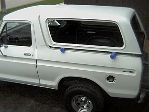 1978 Ford Bronco - This 1978 Ford Bronco, viewed from the side, has a white camper shell and a dented fuel door area.