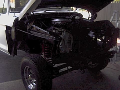 1978 Ford Bronco - Front view of a white 1978 Ford Bronco with its hood open, revealing the engine compartment and suspension system.