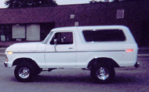 1978 Ford Bronco - Side profile of a white 1978 Ford Bronco, its distinctive body style and chrome wheels.