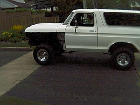 1978 Ford Bronco - White 1978 Ford Bronco parked on asphalt, driver's side front fender removed.