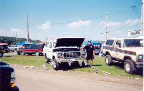 1978 Ford Bronco - A man stands by a white 1978 Ford Bronco with its hood up at an outdoor event.