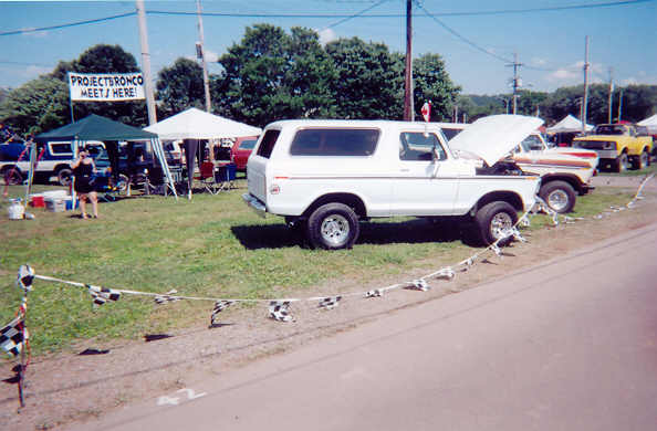 White 1978 Ford Bronco parked at an outdoor event with a "Project Bronco Meets Here" sign