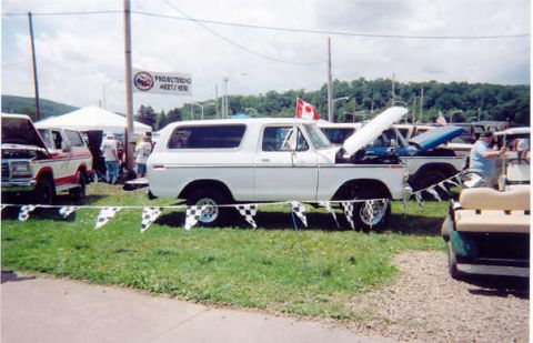 1978 Ford Bronco - White 1978 Ford Bronco on display at a car meet, with its hood open and checkered flags in front.