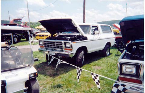 1978 Ford Bronco - A white Ford Bronco is displayed with its hood open at an outdoor event.