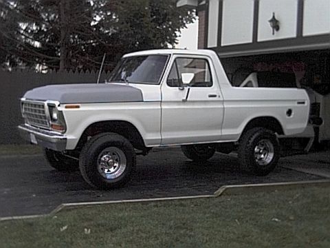 1978 Ford Bronco - A white 1978 Ford Bronco with a grey hood is parked in front of a garage.