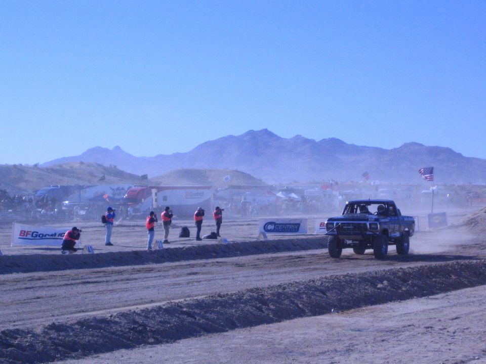 Blue off-road race truck on desert track near pit area