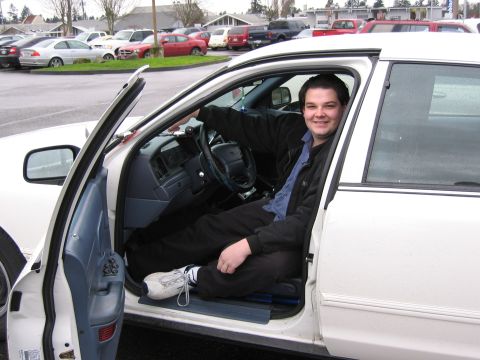 1999 Ford Crown Victoria - A man sits in the driver's seat of a 1999 Ford Crown Victoria, with the door open.