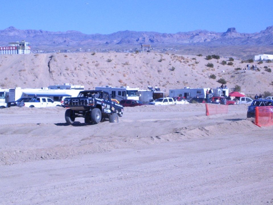 Dark off-road truck on big tires driving across a desert dirt track