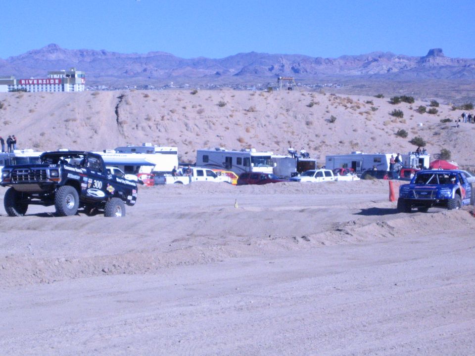 Number 300 dark race truck and a blue race truck on a sandy desert course
