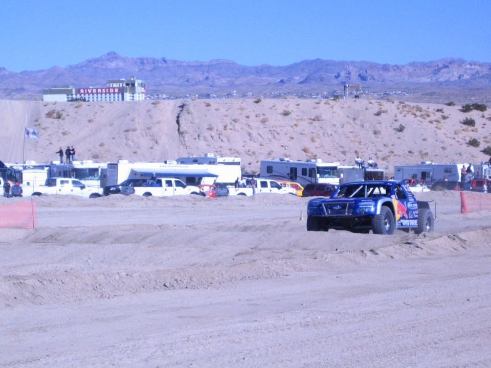 Blue Red Bull off-road race truck cornering on a sandy desert course