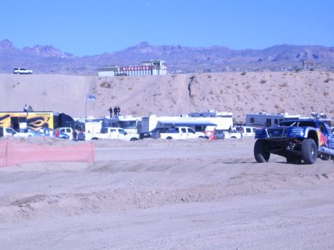 1990 Ford Bronco - blue off-road truck runs a desert course at right, with a yellow Fabtech banner and RVs along the far side.