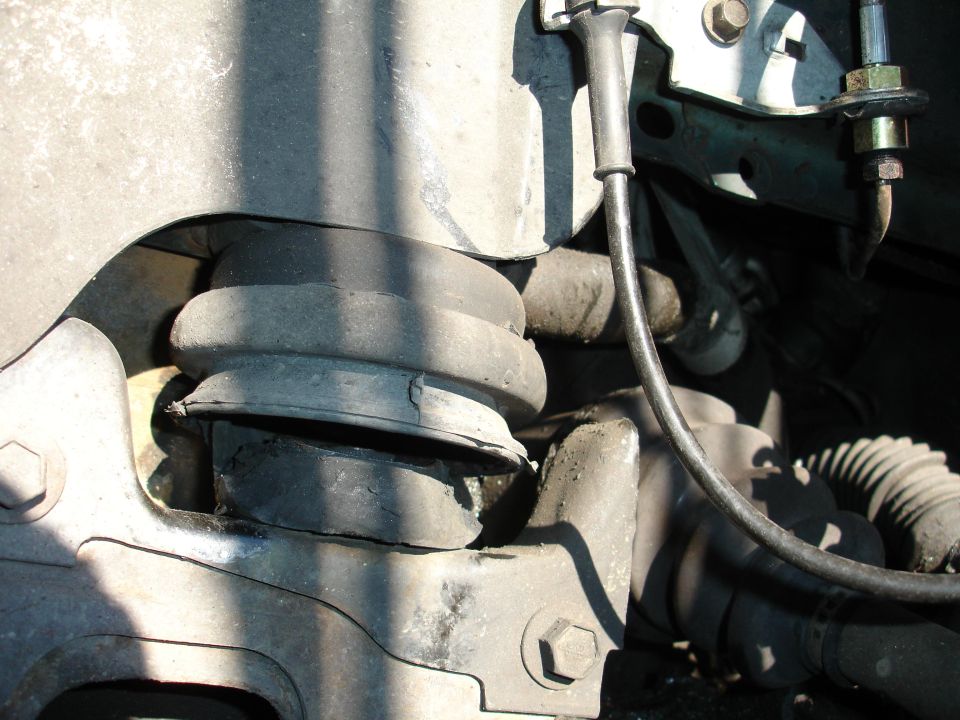 Damaged rubber suspension component with metal bracket and brake line