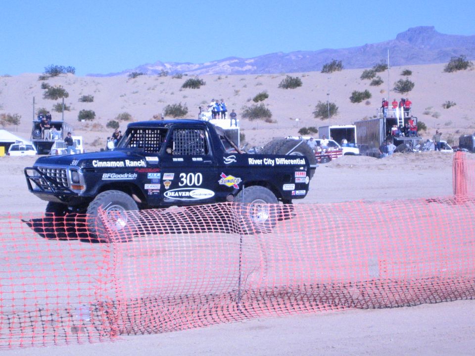 Side view of black number 300 off-road truck on a desert course