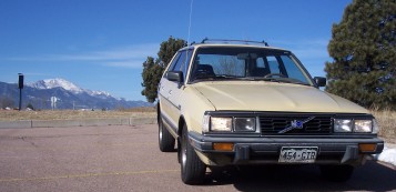 1972 Ford Ranchero - A tan Subaru station wagon is parked in a lot with mountains in the background under a clear blue sky.