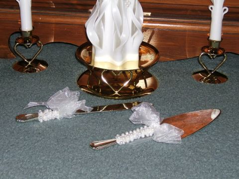 1990 Ford Bronco - A decorated cake knife and server set with white bows and pearl accents is displayed on a carpeted surface.