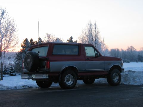 1995 Ford Bronco - A two-tone red and silver 1995 Ford Bronco is parked in a snowy landscape during sunrise.