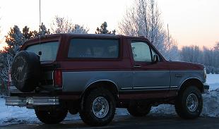 1995 Ford Bronco - This Ford Bronco is a two-tone maroon and grey SUV with a spare tire mounted on the back.