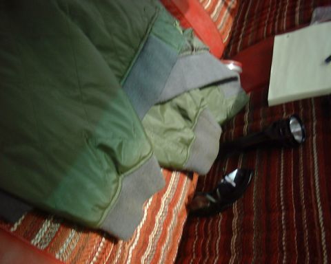 1978 Ford Bronco - A green jacket and a flashlight are placed on a striped blanket or rug.