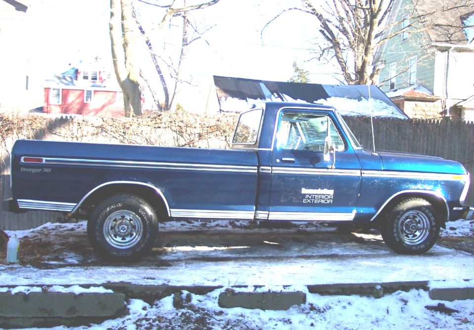 1975 Ford F-150 Ranger XLT pickup truck, side view. Truck is blue with chrome trim and white lettering on the door