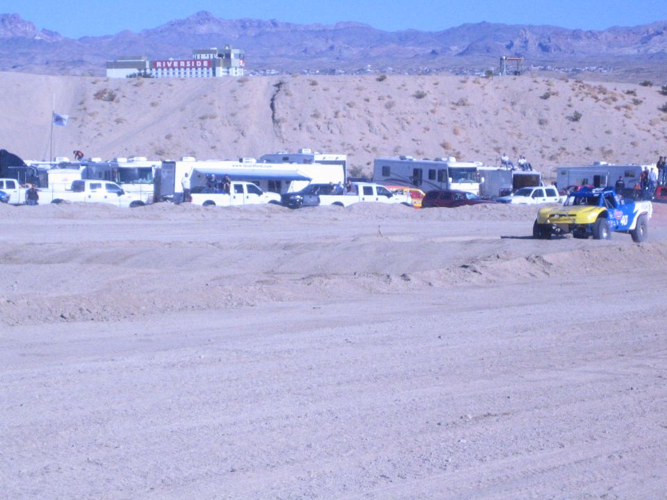 Yellow and blue race truck on dirt track with RVs and Riverside casino in background