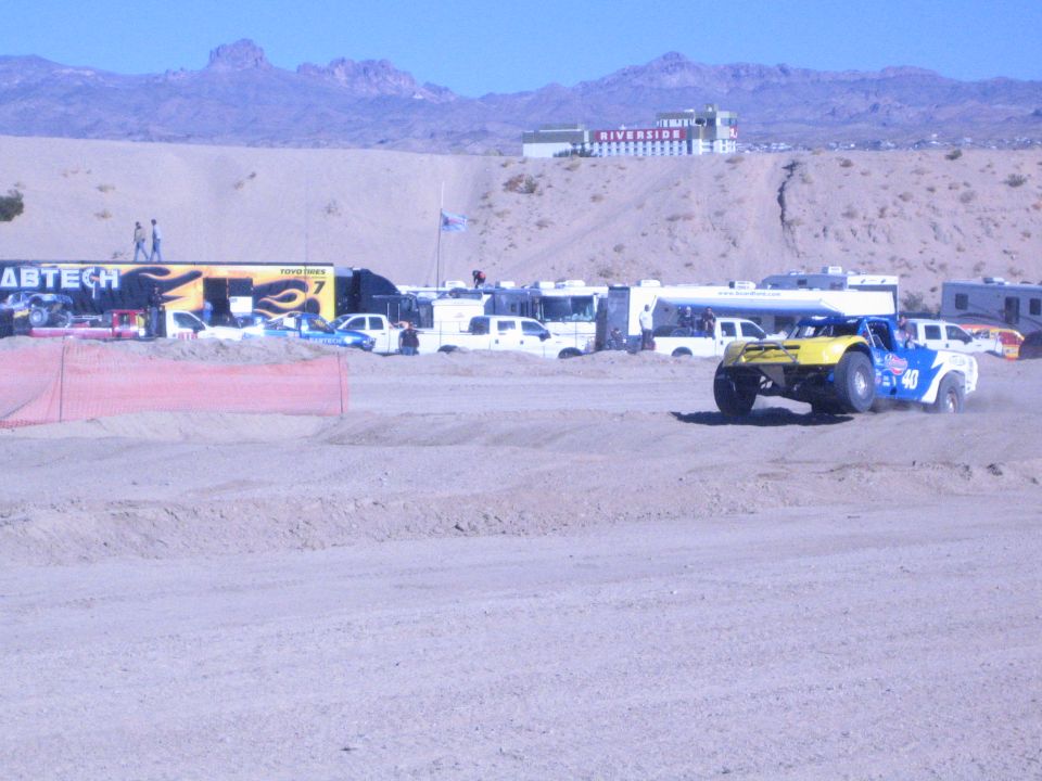 Number 40 yellow and blue race truck on dirt track past Fabtech hauler