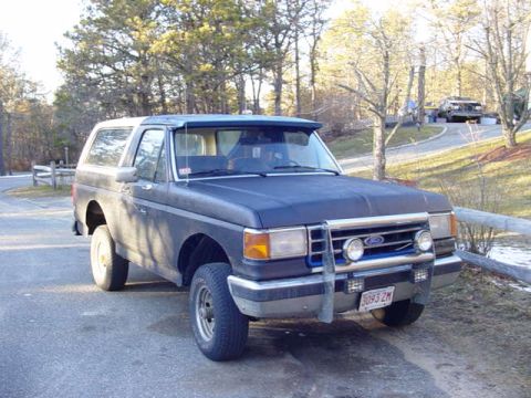 1989 Ford Bronco - This 1989 Ford Bronco is parked outdoors near a wooded area. A second vehicle is visible in the distance.