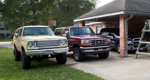 1978 Dodge Power Ram - Three pickup trucks are parked in a driveway. The front vehicle is a lifted 1978 Dodge Power Ram.