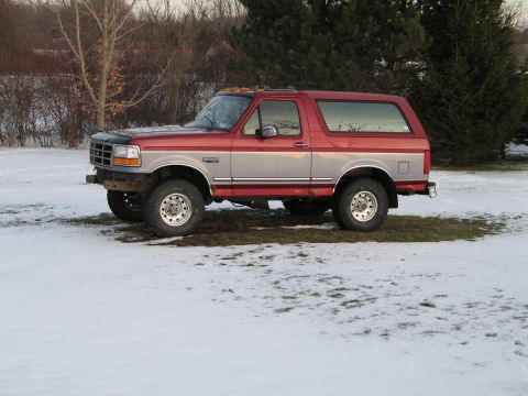 1995 Ford Bronco - This 1995 Ford Bronco features a two-tone red and silver paint scheme and is parked in a snowy outdoor setting.