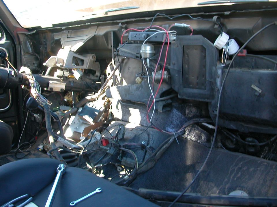 Disassembled dashboard interior with exposed wiring and tools on seat