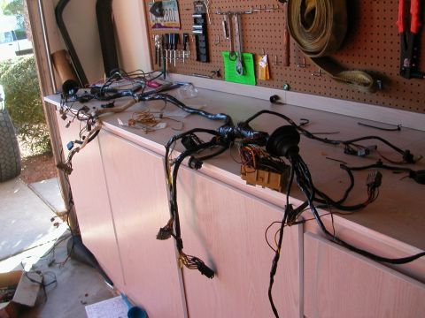 1984 Ford Bronco - A complex wiring harness is laid out on a workbench, with various connectors and a fuse box visible.