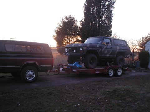 1979 Ford Bronco - A Ford Bronco is loaded onto a trailer, hitched to a pickup truck, at dusk.