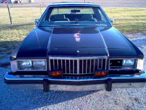 1985 Ford LTD Crown Victoria - Front view of a 1985 Ford Crown Victoria LTD, a dark sedan with a prominent chrome grille and rectangular headlights.