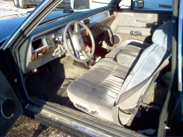 Gray velour interior of older sedan seen through open driver's door