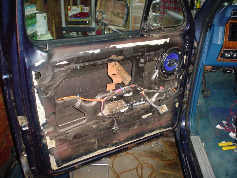Car door interior with exposed wiring and blue speaker