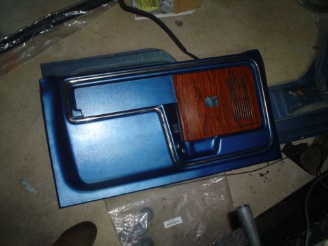 1984 Ford Bronco - A blue door panel with wood grain insert and chrome trim is shown.