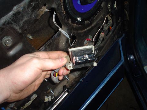 1984 Ford Bronco - Close-up of a hand disconnecting an electrical component from a vehicle's interior door panel.