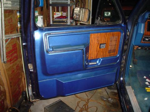1984 Ford Bronco - Close-up of the interior door panel of a 1984 Ford Bronco, blue vinyl and wood grain accents.