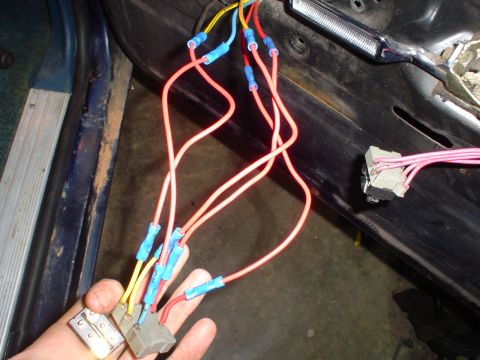 1984 Ford Bronco - A hand holds a wiring harness with multiple connectors, showing the interior electrical components of a vehicle.